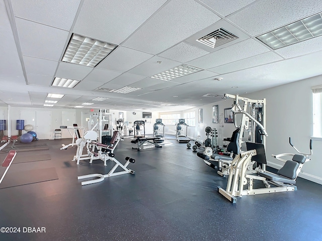 exercise room with a drop ceiling and a healthy amount of sunlight