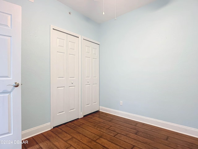 unfurnished bedroom with dark hardwood / wood-style flooring and multiple closets