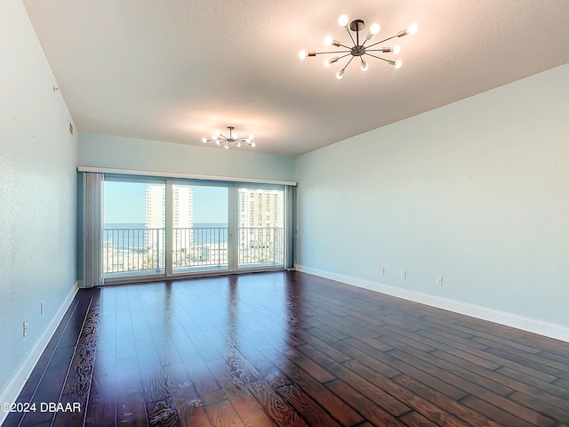 spare room with a water view, dark hardwood / wood-style floors, and a notable chandelier