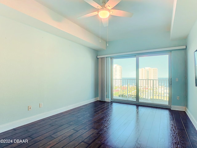 unfurnished room featuring dark hardwood / wood-style floors, ceiling fan, and a water view