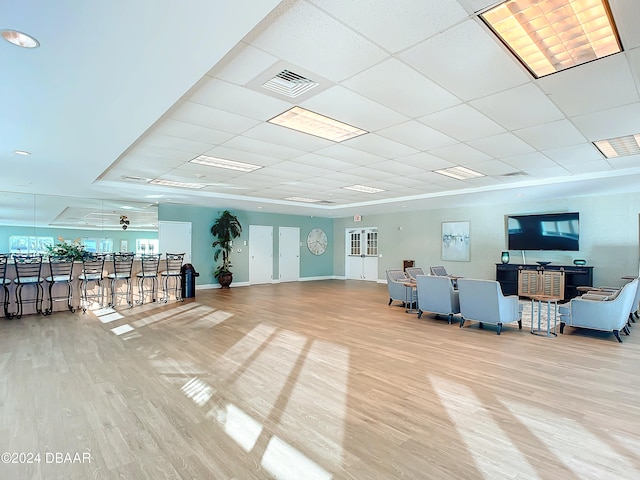 exercise room with a paneled ceiling, light hardwood / wood-style floors, and ceiling fan