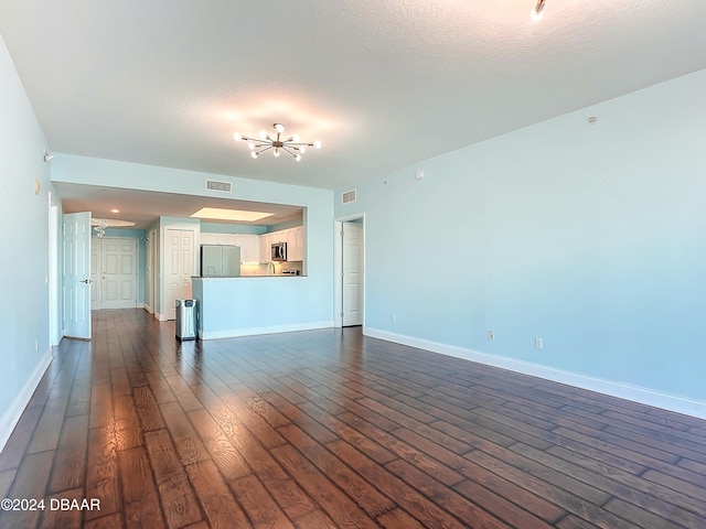 unfurnished living room featuring dark wood-type flooring and a textured ceiling