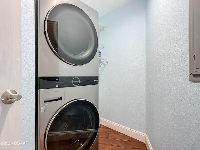 washroom featuring electric panel, stacked washing maching and dryer, and hardwood / wood-style flooring