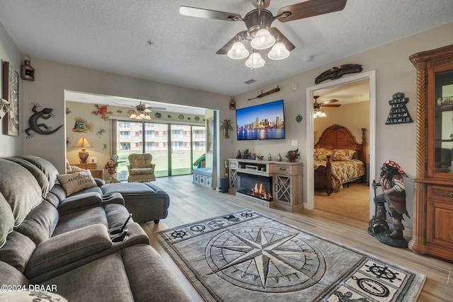 99 Broad River Pl Unit 3103, Welaka, FL 32193 - living room with a ceiling fan, a textured ceiling, light wood-type flooring, and a glass covered fireplace
