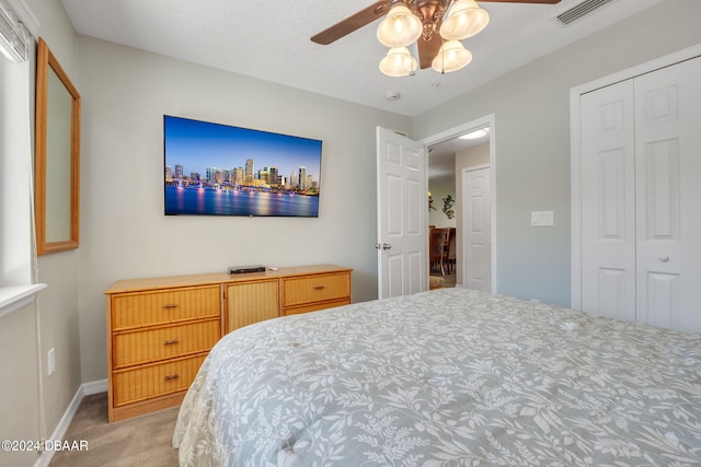 bedroom with ceiling fan, a closet, and light colored carpet