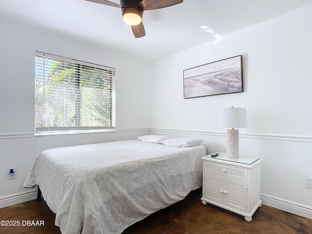 bedroom with dark hardwood / wood-style flooring, a baseboard heating unit, and ceiling fan