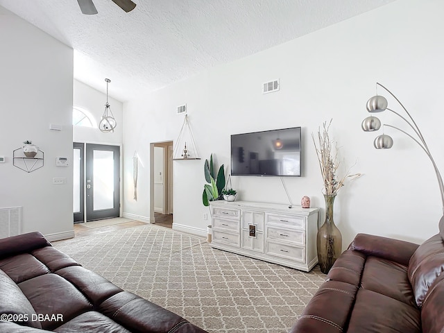 living room featuring ceiling fan, high vaulted ceiling, and a textured ceiling