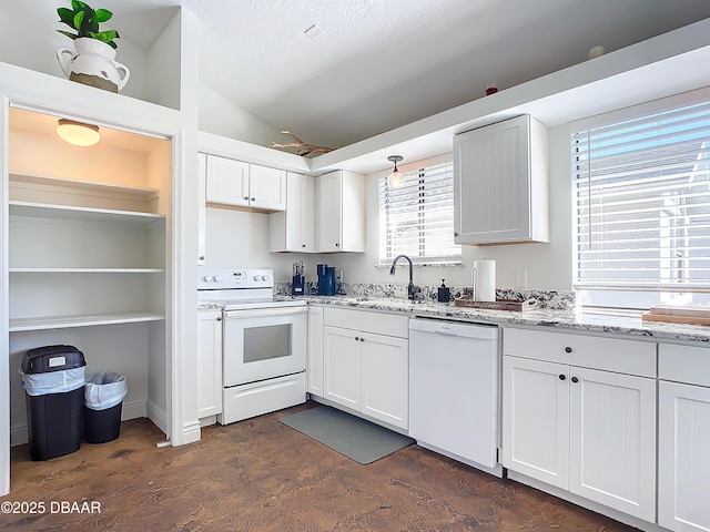 kitchen with light stone countertops, sink, white cabinets, and white appliances