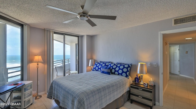 bedroom with a textured ceiling, a water view, multiple windows, and ceiling fan