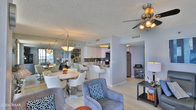 dining room featuring ceiling fan, a textured ceiling, and light wood-type flooring