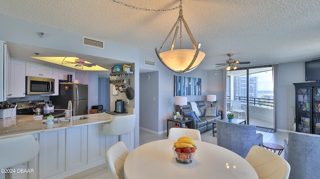 dining space with light hardwood / wood-style flooring, a textured ceiling, and ceiling fan