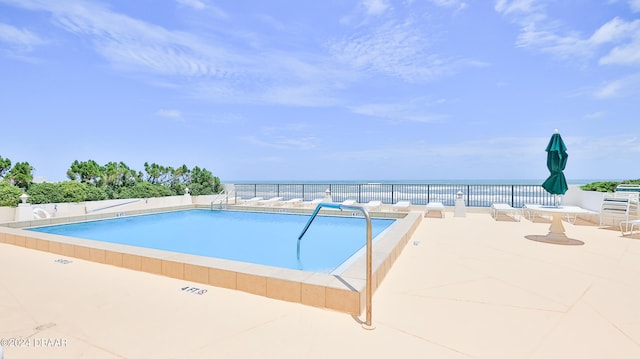 view of swimming pool with a patio and a water view