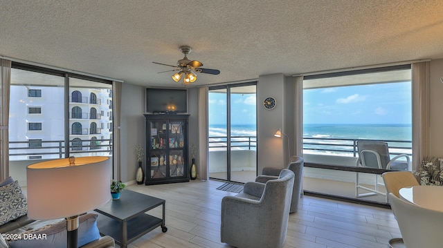 living room featuring expansive windows, hardwood / wood-style floors, ceiling fan, and a textured ceiling