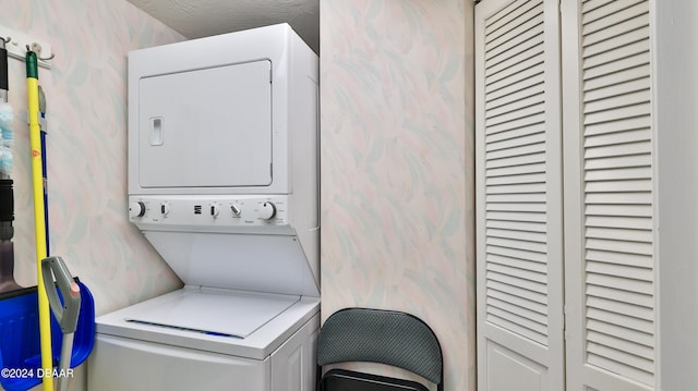 laundry room featuring a textured ceiling and stacked washer / dryer