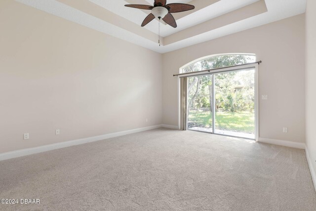 spare room with carpet flooring, ceiling fan, and a raised ceiling