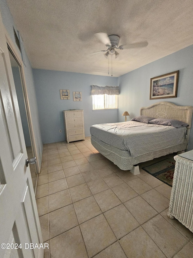 tiled bedroom featuring ceiling fan and a textured ceiling