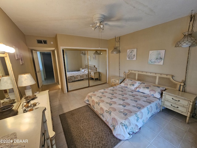 bedroom featuring tile patterned floors, ceiling fan, a closet, and a textured ceiling