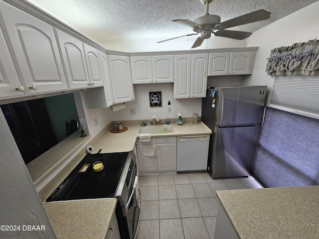 kitchen featuring sink, light tile patterned floors, a textured ceiling, white cabinets, and appliances with stainless steel finishes