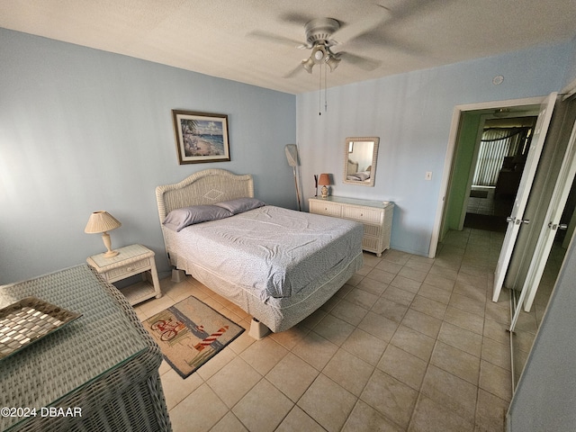 tiled bedroom with ceiling fan and a textured ceiling