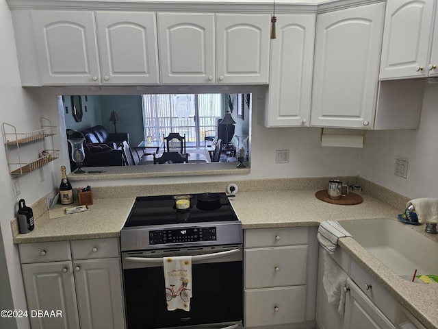 kitchen featuring stainless steel range, white cabinets, and sink