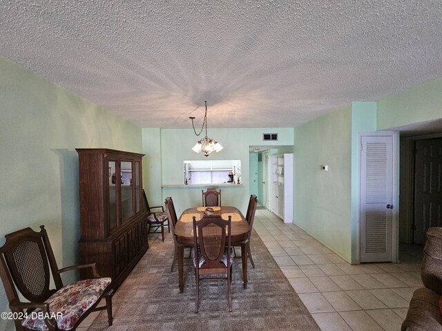 dining area featuring a chandelier, a textured ceiling, and light tile patterned flooring