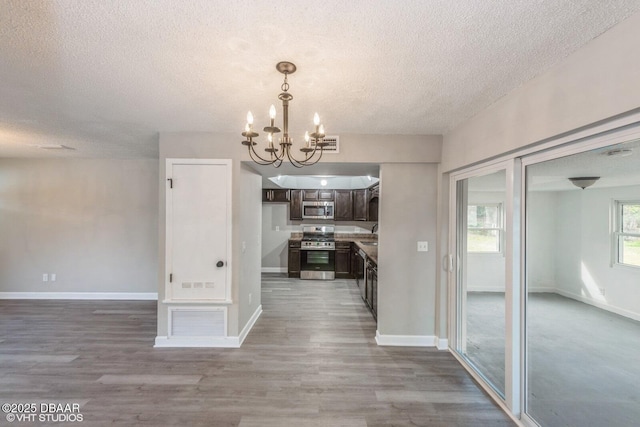 unfurnished dining area featuring a notable chandelier, hardwood / wood-style flooring, and a textured ceiling