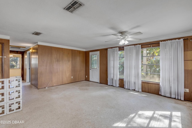 empty room with crown molding, ceiling fan, and wood walls