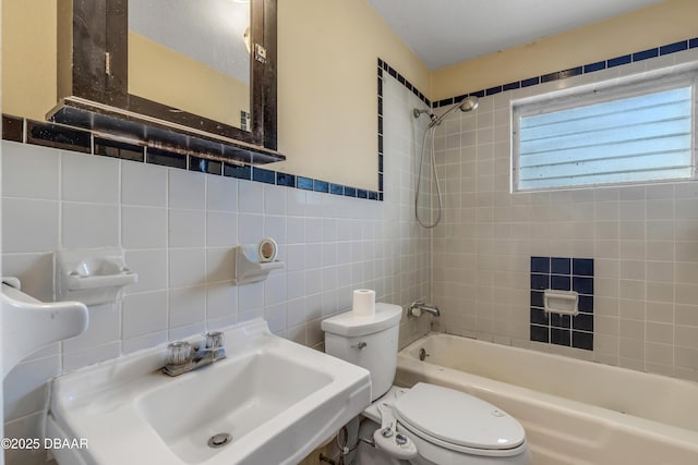 full bathroom with toilet, tiled shower / bath combo, sink, and tile walls