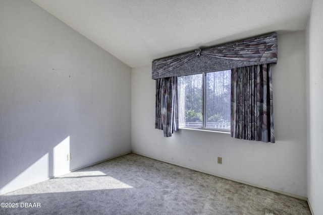 spare room with carpet floors, a textured ceiling, and vaulted ceiling