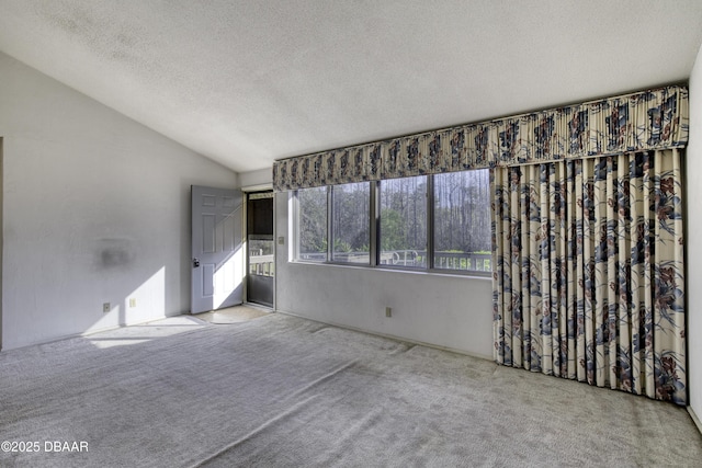 unfurnished room featuring a textured ceiling, carpet flooring, and vaulted ceiling