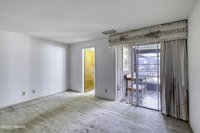 unfurnished room with carpet flooring, a healthy amount of sunlight, a textured ceiling, and visible vents