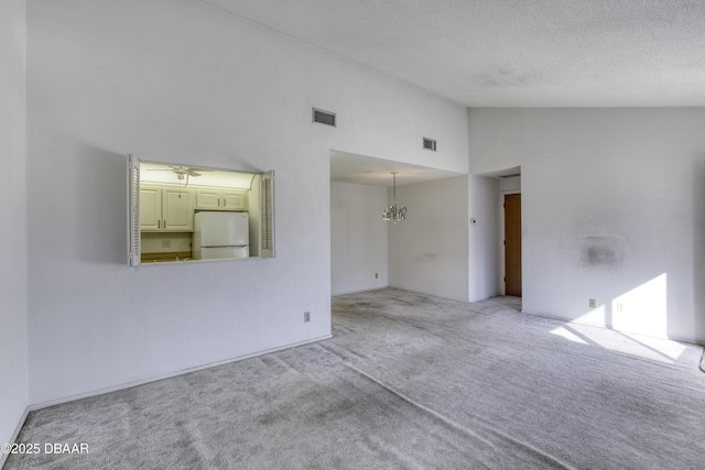 unfurnished room with an inviting chandelier, carpet flooring, visible vents, and high vaulted ceiling