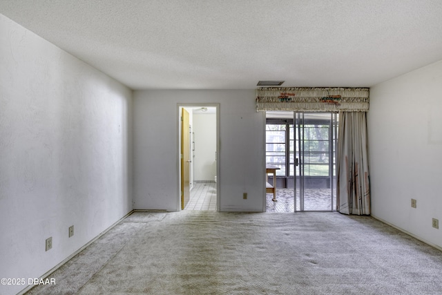 carpeted empty room with visible vents and a textured ceiling