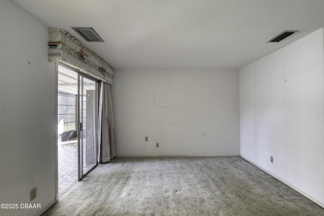 carpeted spare room featuring visible vents and a textured ceiling