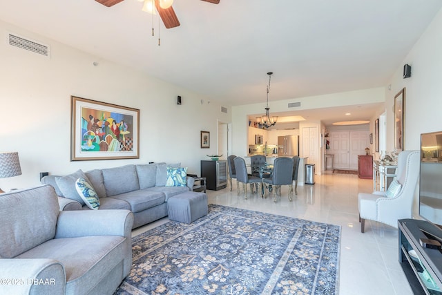 living area featuring light tile patterned floors, visible vents, and ceiling fan with notable chandelier