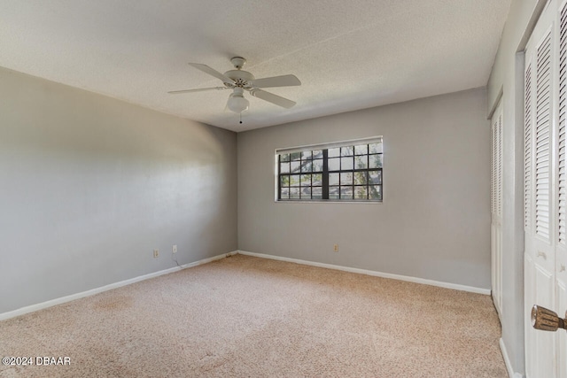 unfurnished bedroom with ceiling fan, light colored carpet, and a textured ceiling