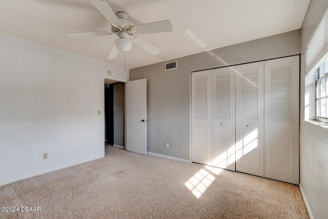 unfurnished bedroom featuring a textured ceiling, ceiling fan, light carpet, and a closet