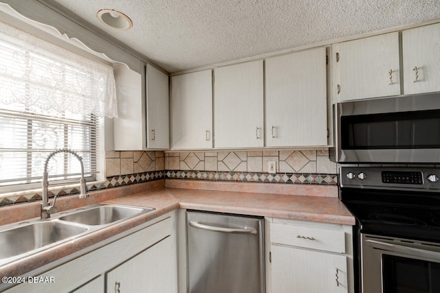 kitchen featuring white cabinets, sink, decorative backsplash, a textured ceiling, and appliances with stainless steel finishes