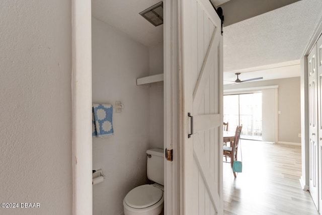 bathroom featuring hardwood / wood-style floors, ceiling fan, toilet, and a textured ceiling