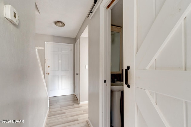 hall featuring a barn door and light hardwood / wood-style flooring