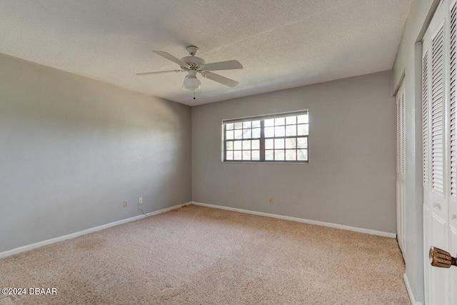 unfurnished bedroom with ceiling fan, light colored carpet, and a textured ceiling