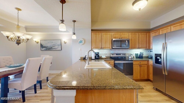 kitchen featuring sink, stainless steel appliances, a notable chandelier, pendant lighting, and light wood-type flooring