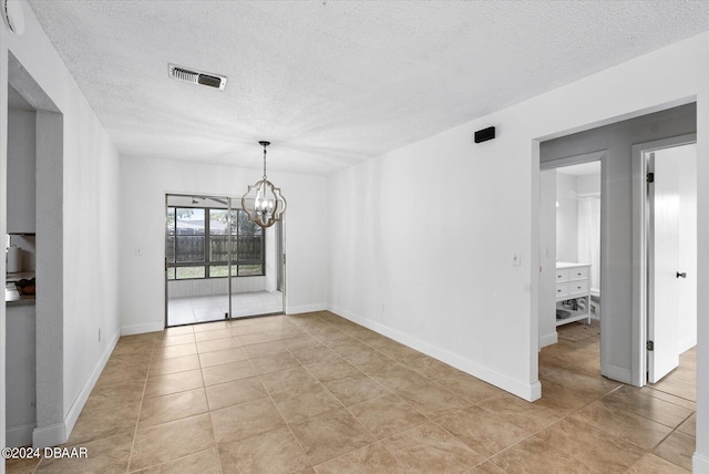 tiled empty room featuring a chandelier and a textured ceiling