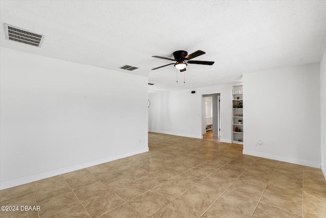 tiled spare room with a textured ceiling and ceiling fan