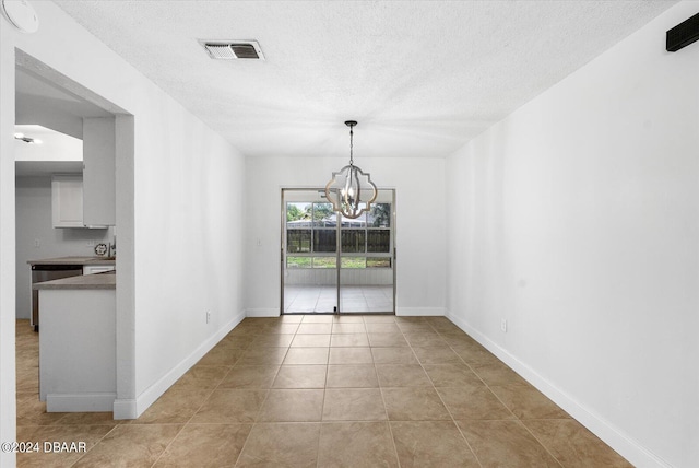 unfurnished dining area featuring a textured ceiling, a notable chandelier, and light tile patterned floors