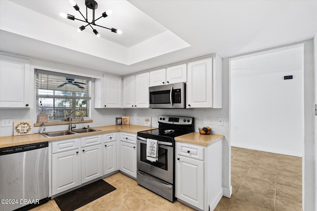 kitchen featuring stainless steel appliances, an inviting chandelier, light tile patterned floors, sink, and white cabinetry