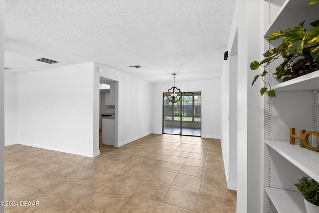 tiled empty room with a textured ceiling and a chandelier