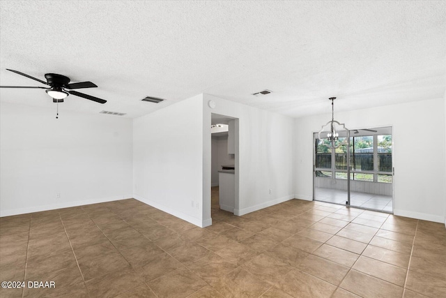 empty room featuring ceiling fan with notable chandelier, a textured ceiling, and light tile patterned floors