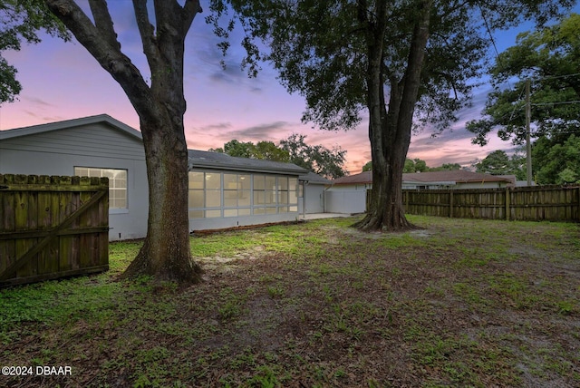 yard at dusk featuring a sunroom