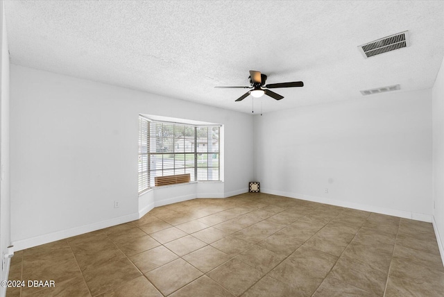 empty room with a textured ceiling, tile patterned flooring, and ceiling fan